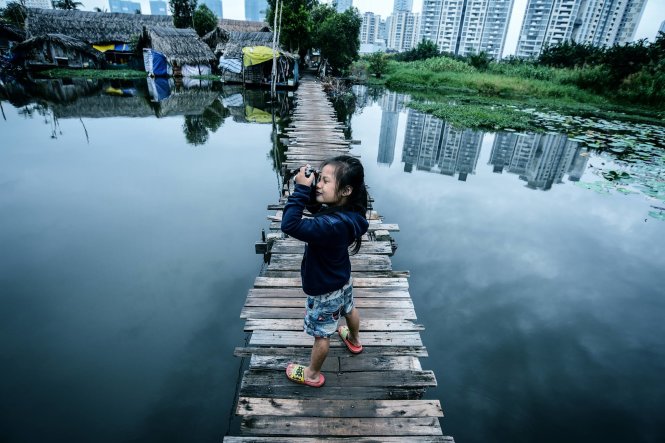Bé Quỳnh (5 tuổi rưỡi, quê An Giang, cha mẹ làm thợ hồ, cả nhà sống tại lán trại xây dựng ở Q.2) trong lần đầu tiên cầm một chiếc máy ảnh - Sài Gòn, tháng 12-2015